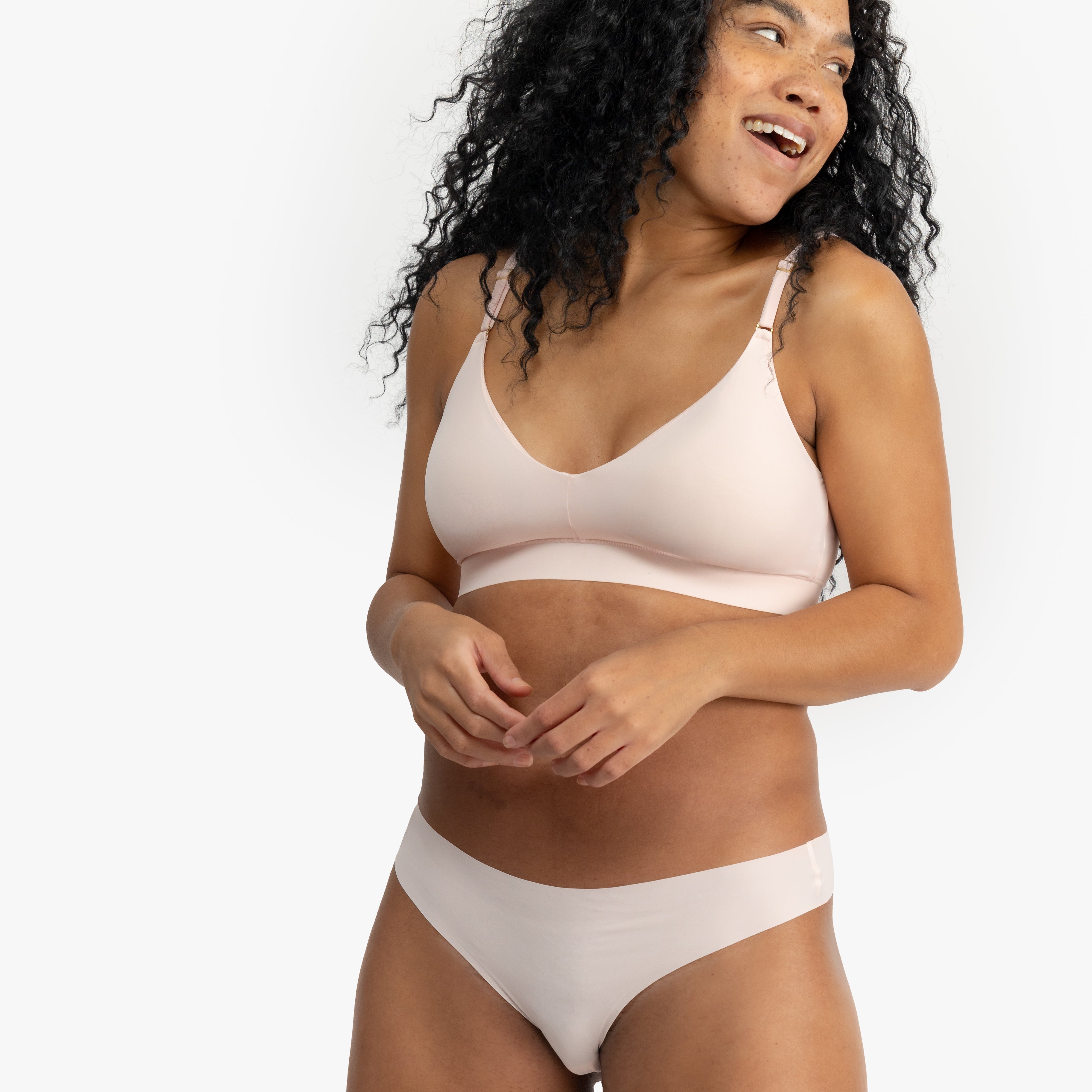 Woman wearing a rose quartz soft seamless thong underwear on white background.