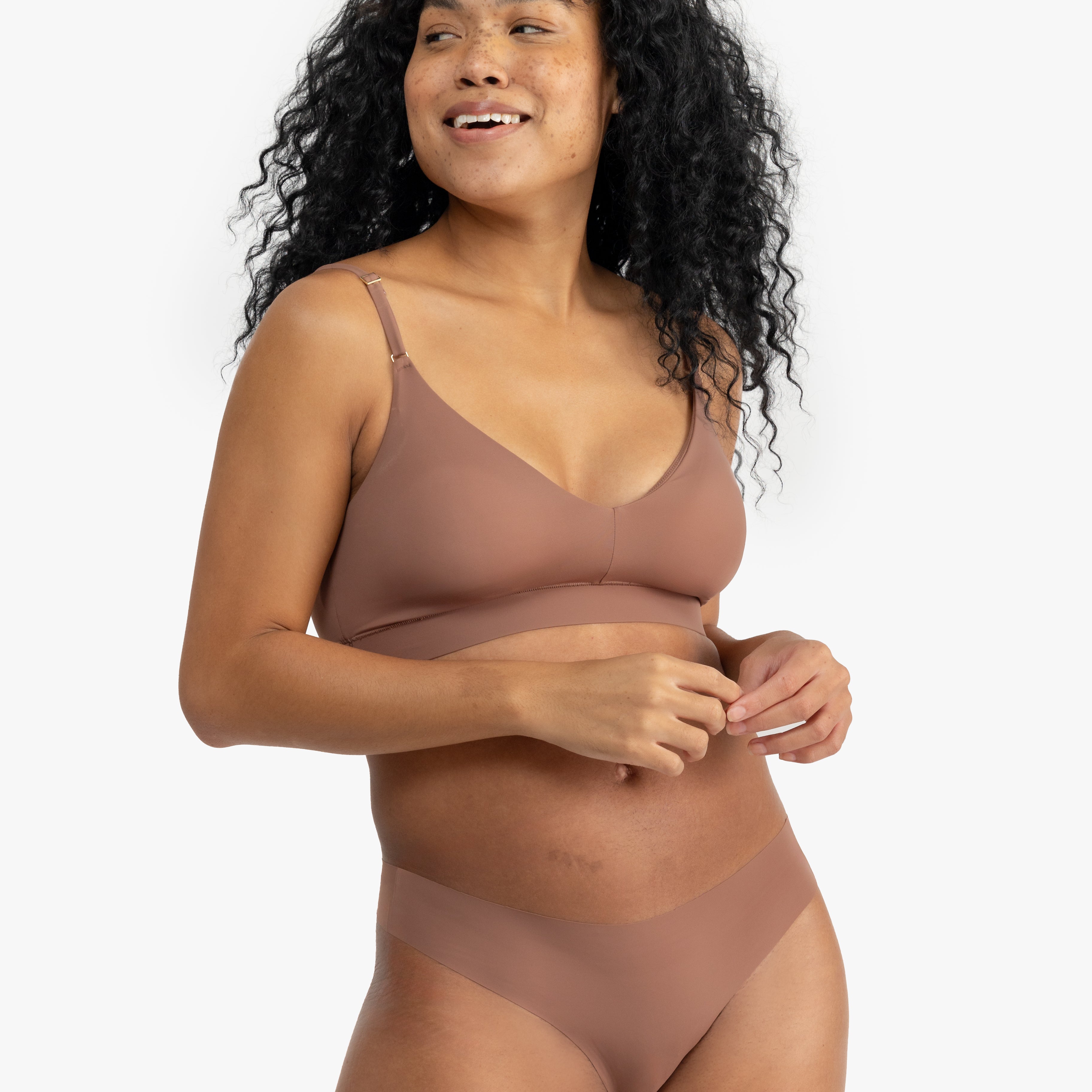 A woman wearing a toffee soft seamless thong underwear on white background.