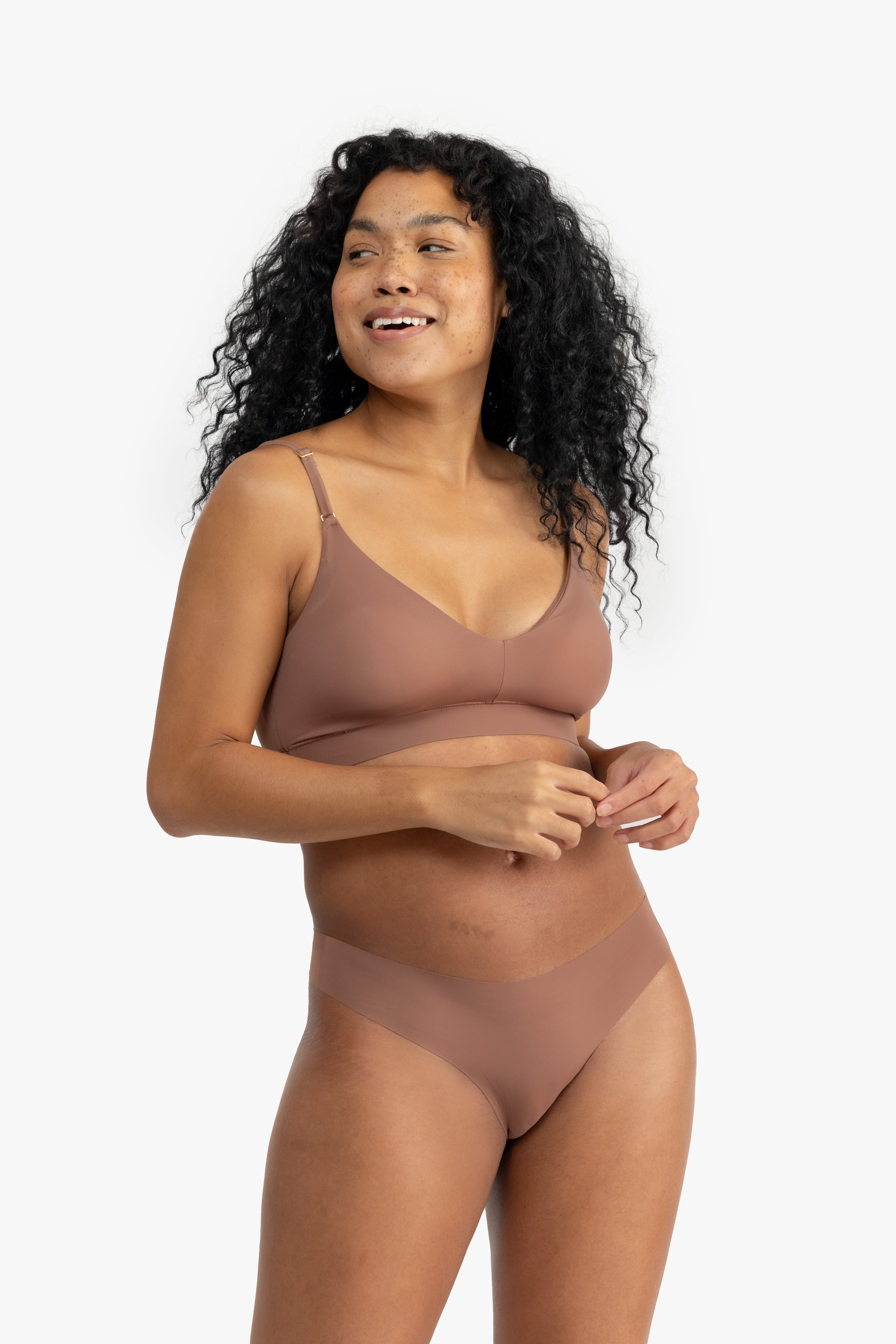 A woman wearing a toffee soft seamless thong underwear on white background.