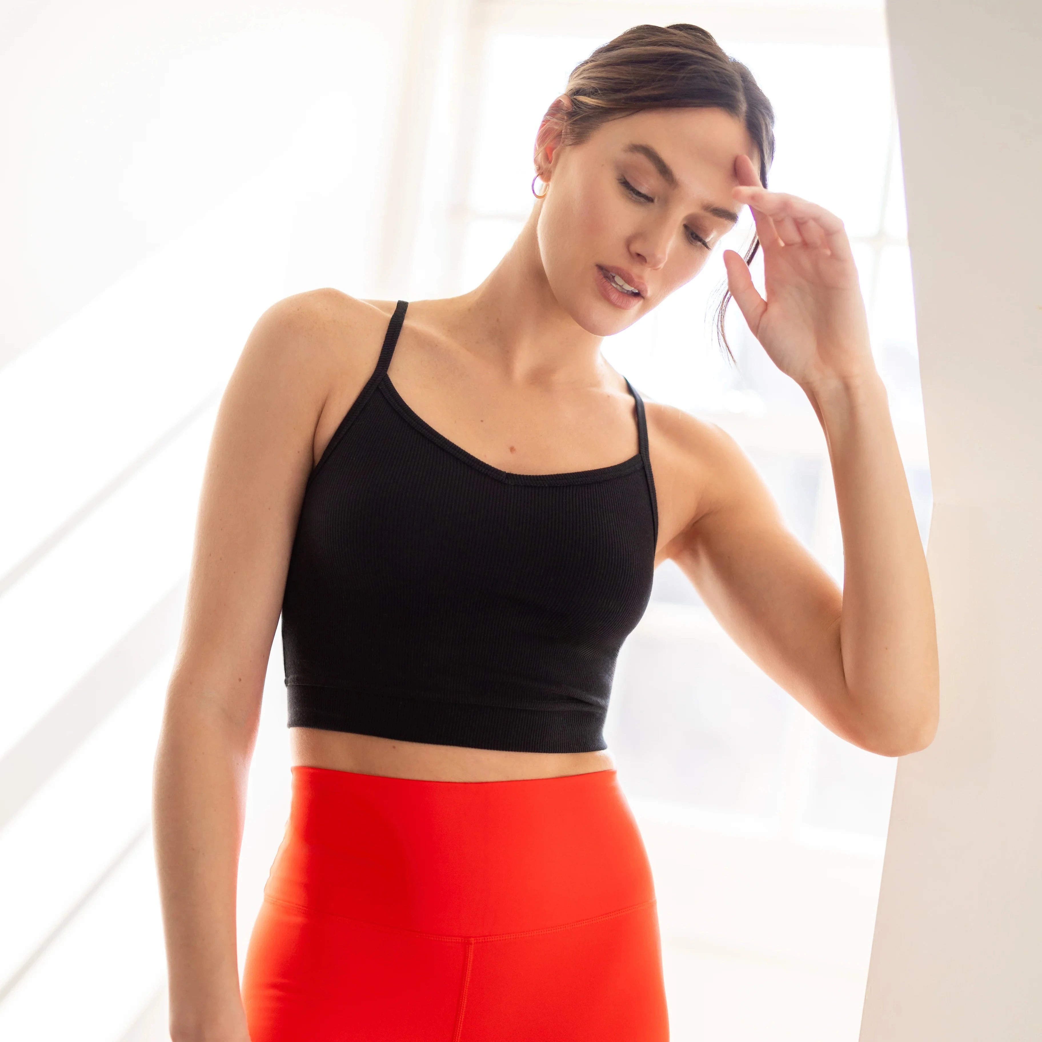 Woman wearing a black sports bra and red leggings indoors.