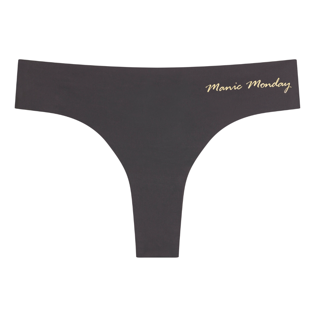 A shale soft seamless thong with 'Manic Monday' written in gold on the front.