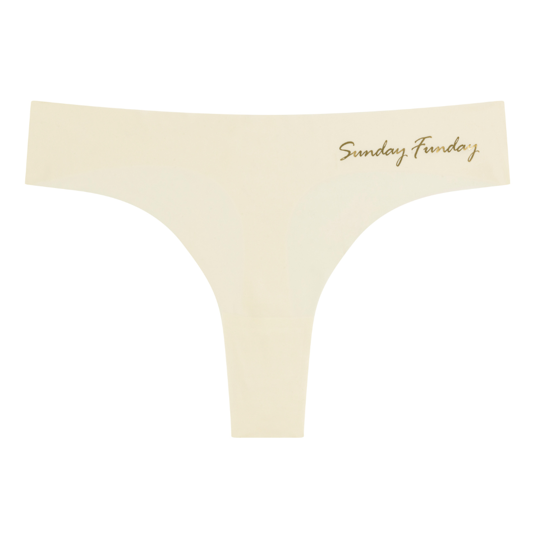 A Winter White soft seamless thong with 'Sunday Funday' written in gold on the front.
