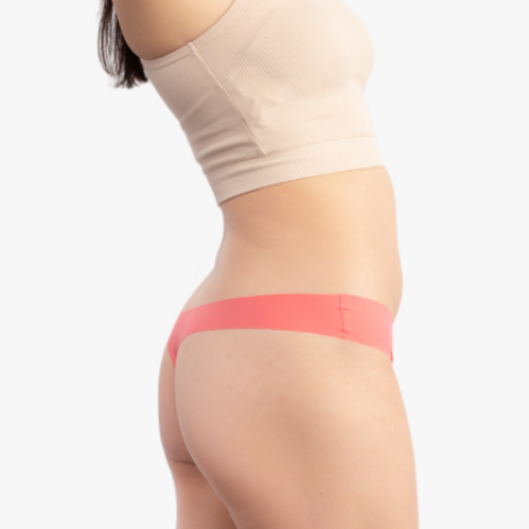 A woman wearing a calypso coral soft seamless thong underwear on white background.