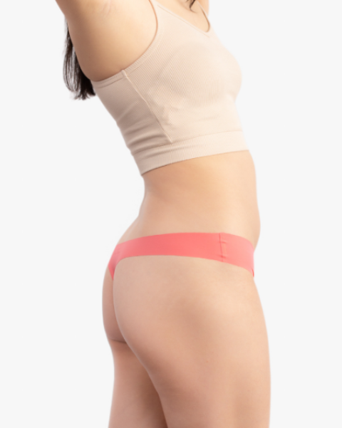 A woman wearing a calypso coral soft seamless thong underwear on white background.