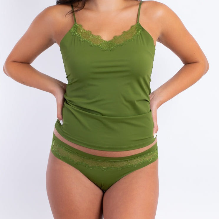 A woman wearing a green soft seamless camisole with delicate lace detail at the neckline, with adjustable straps.