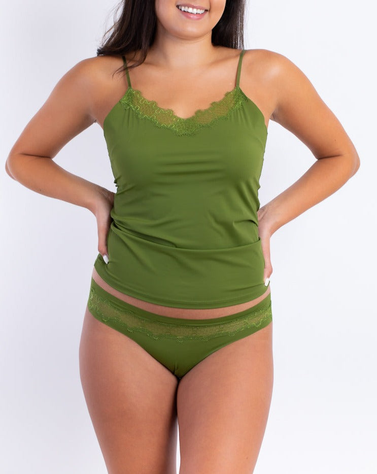 A woman wearing a green soft seamless camisole with delicate lace detail at the neckline, with adjustable straps.