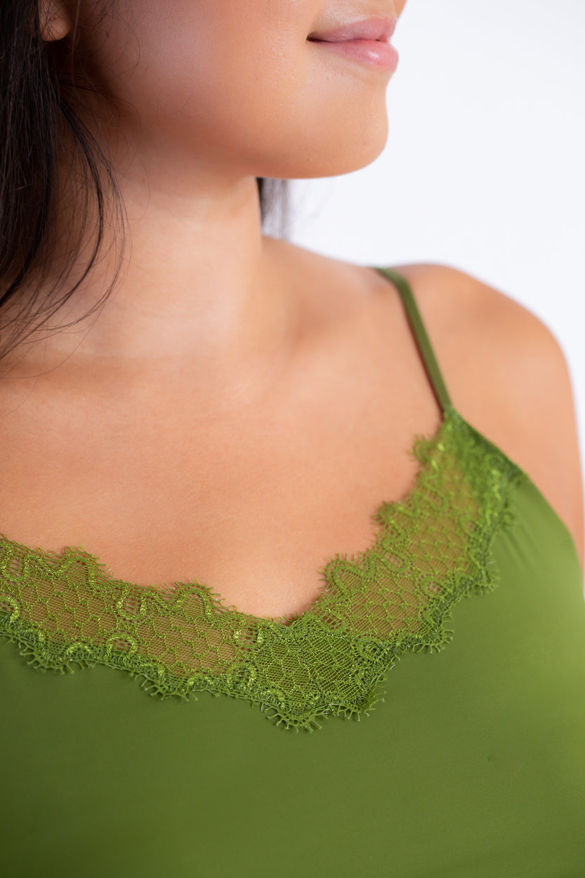 A woman wearing a green soft seamless camisole with delicate lace detail at the neckline, with adjustable straps.