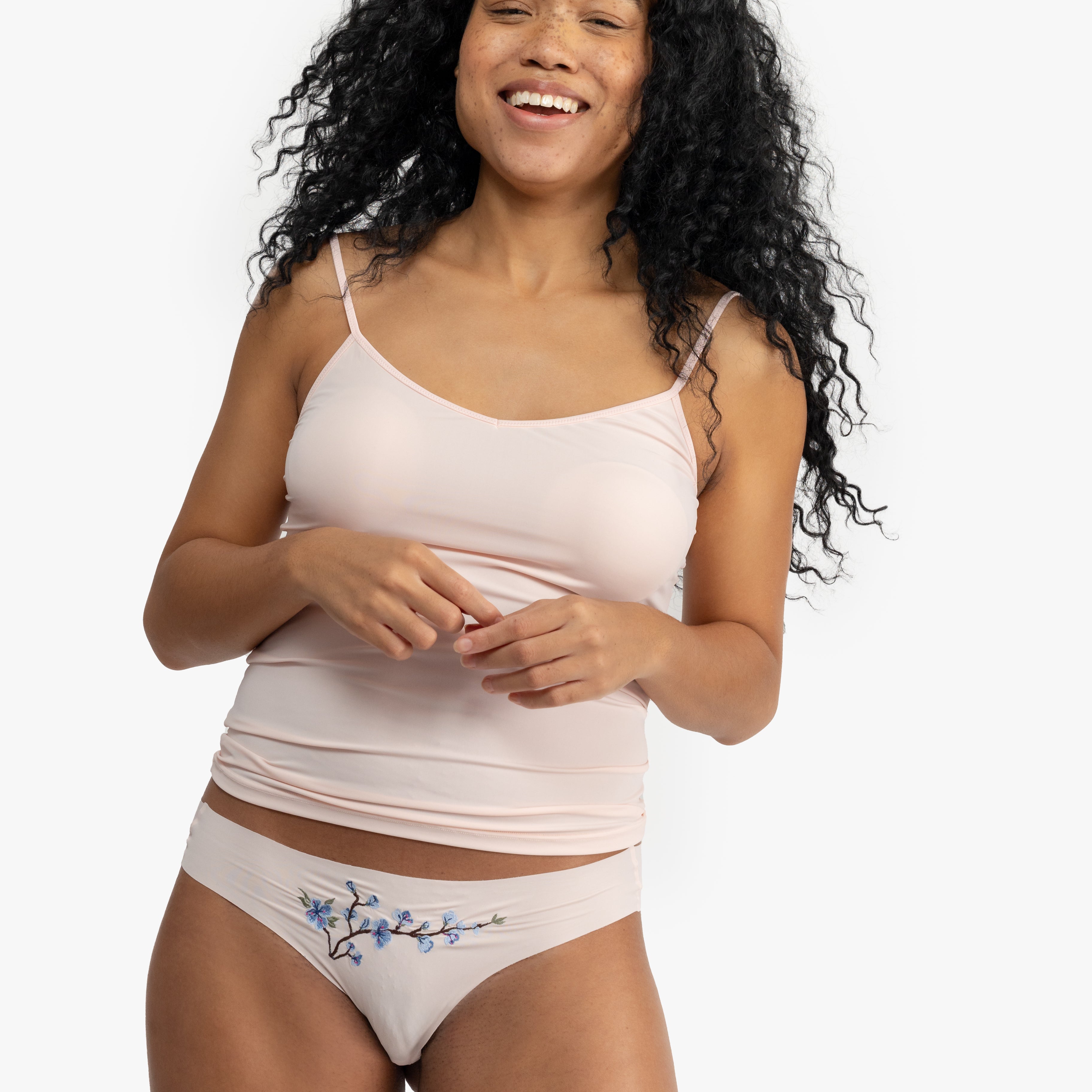 Woman wearing a soft seamless camisole with adjustable spaghetti straps and a V-neckline on white background.