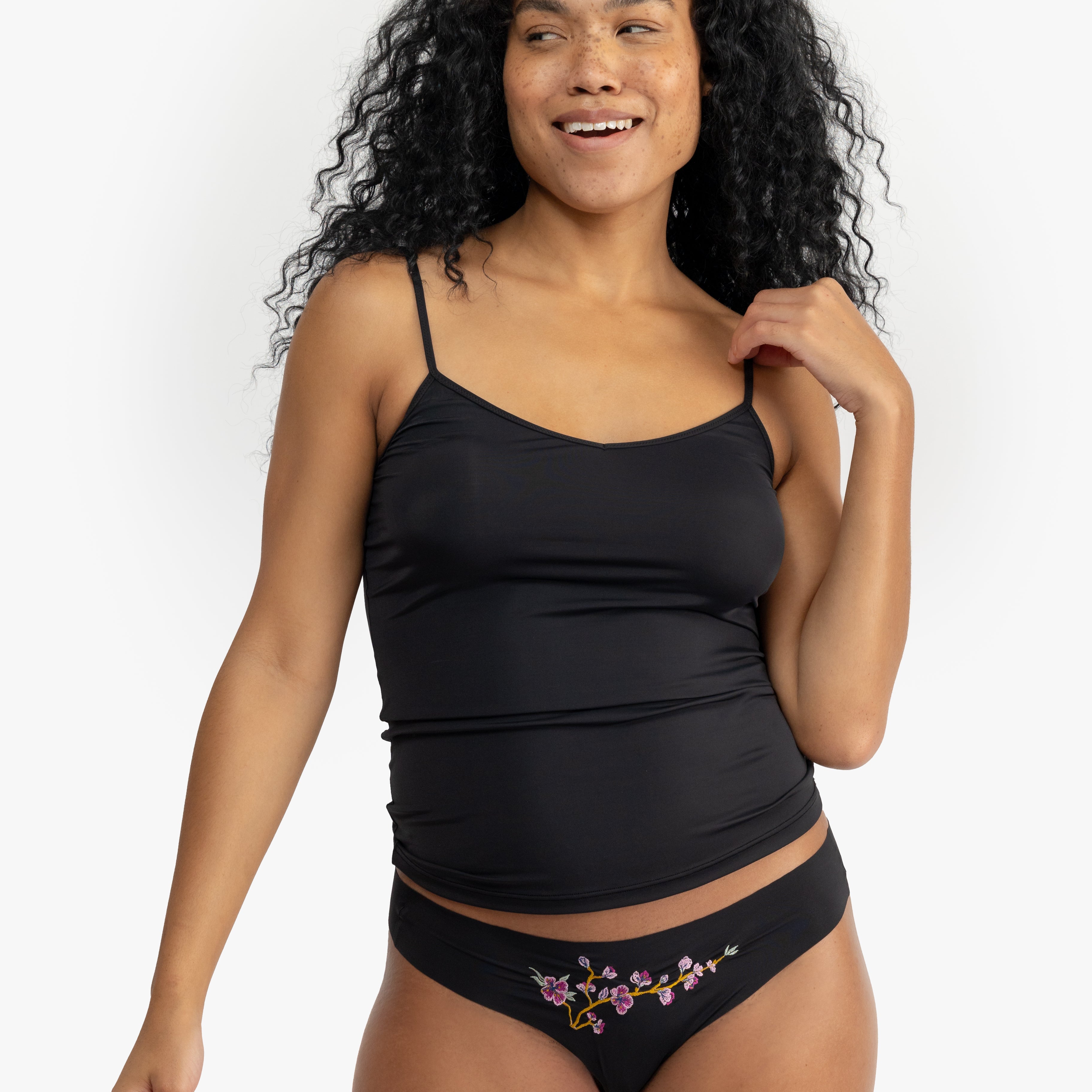 Woman wearing a Tap Shoe Black soft seamless camisole with adjustable spaghetti straps and a V-neckline on white background.