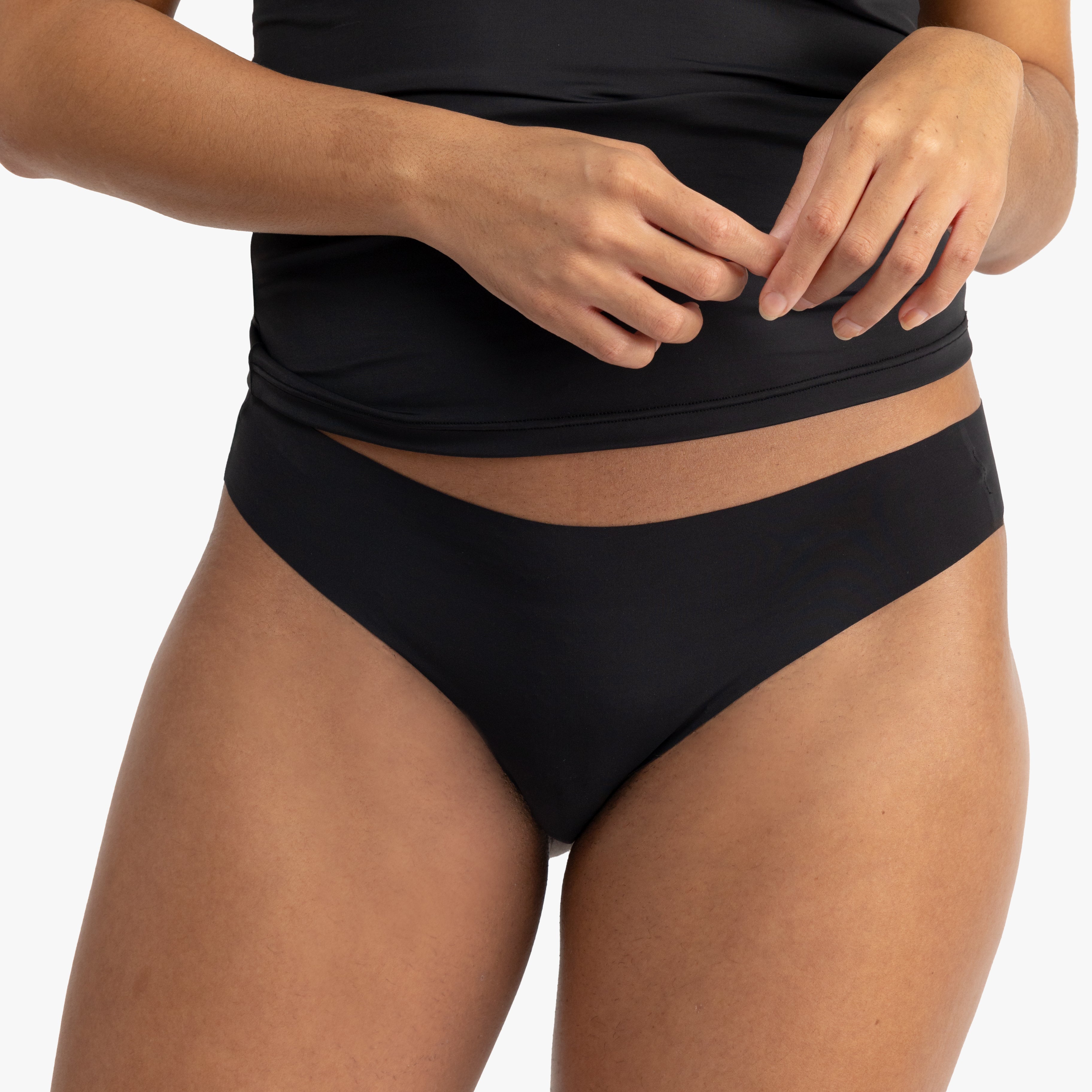 A woman wearing a tap shoe black soft seamless thong underwear on white background.