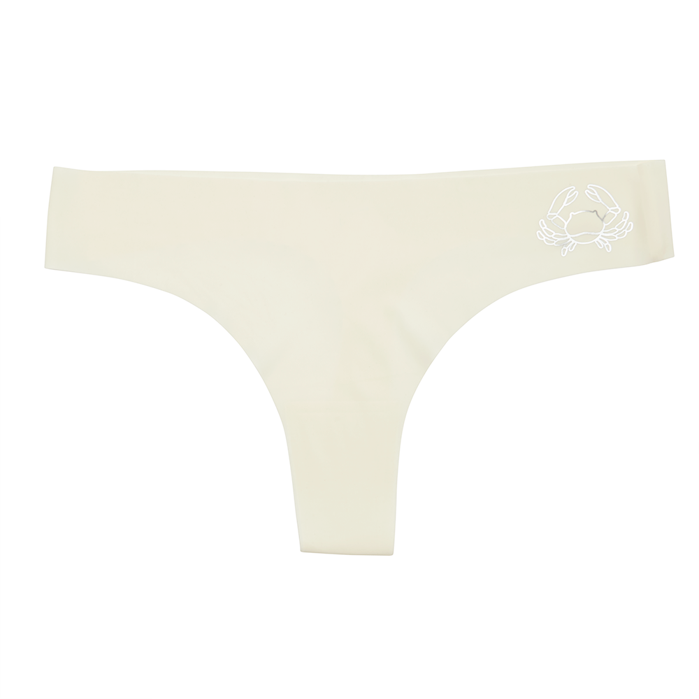 This image features a sleek white thong with a distinctive metallic silver decal of a zodiac sign on the waistband. The thong is designed with a cotton gusset for superior hygiene and is constructed with thermowelded side seams and removable tags for comfort.