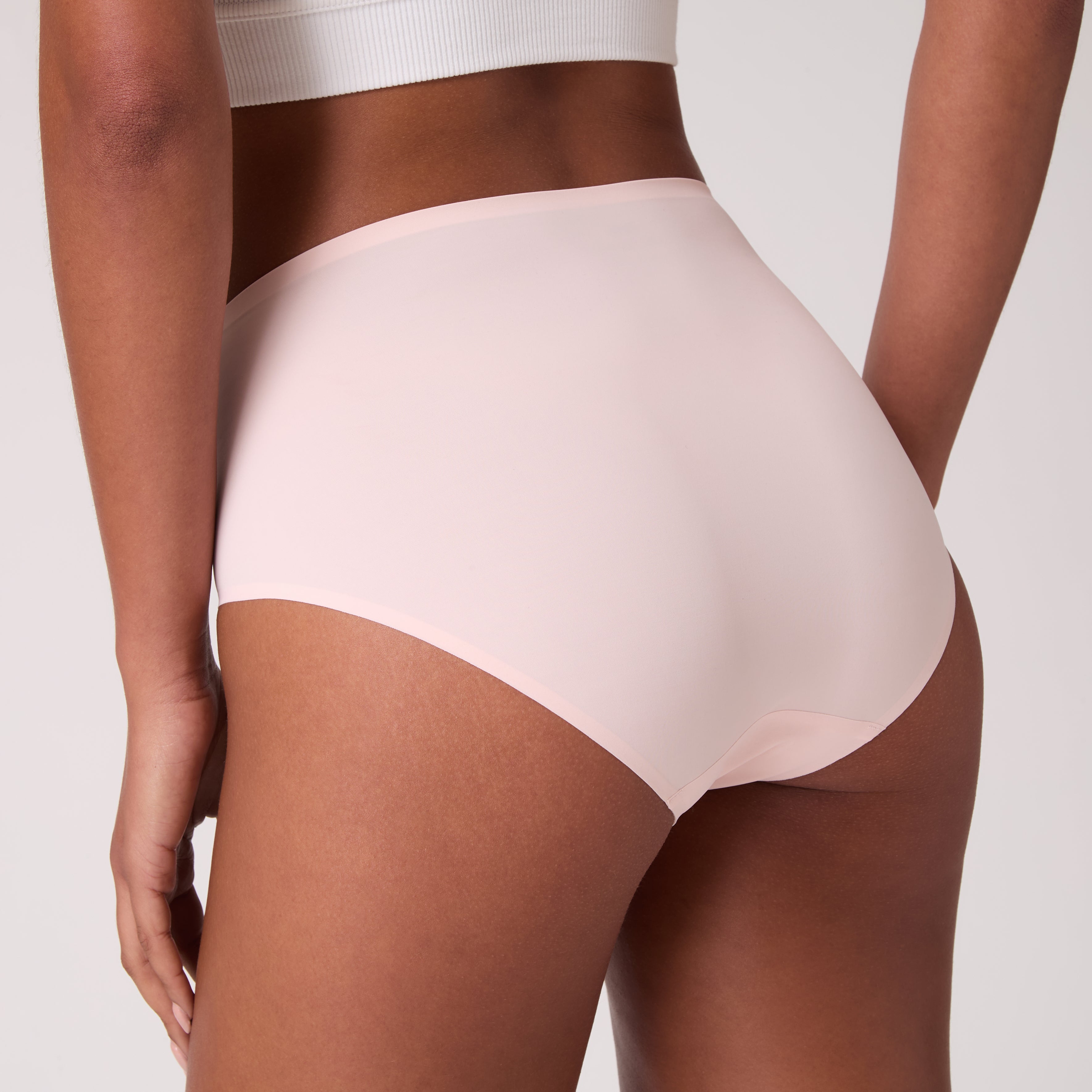 Back view of model wearing Rose Quartz UW Soft Seamless High Waist Brief on white background.