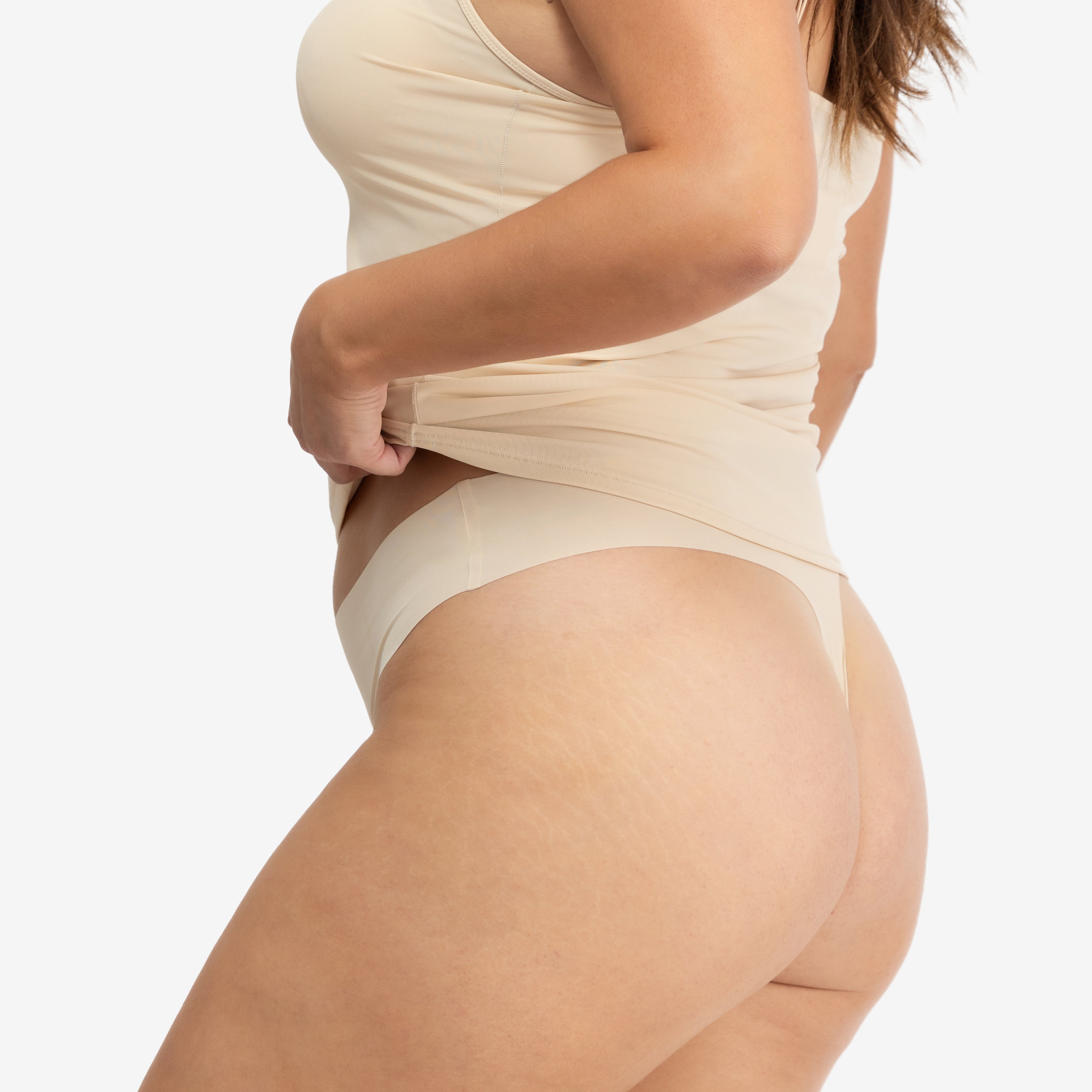 A woman wearing a smoke grey soft seamless thong underwear on white background.