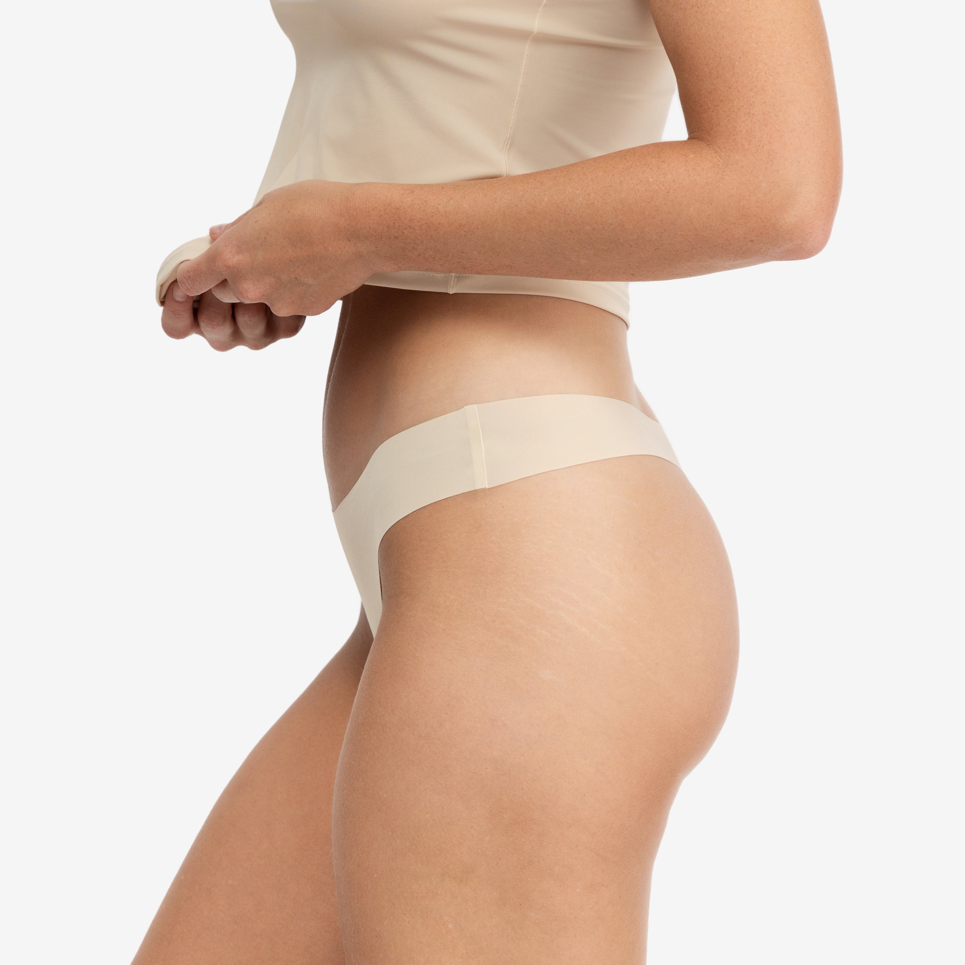 A woman wearing a smoke grey soft seamless thong underwear on white background.