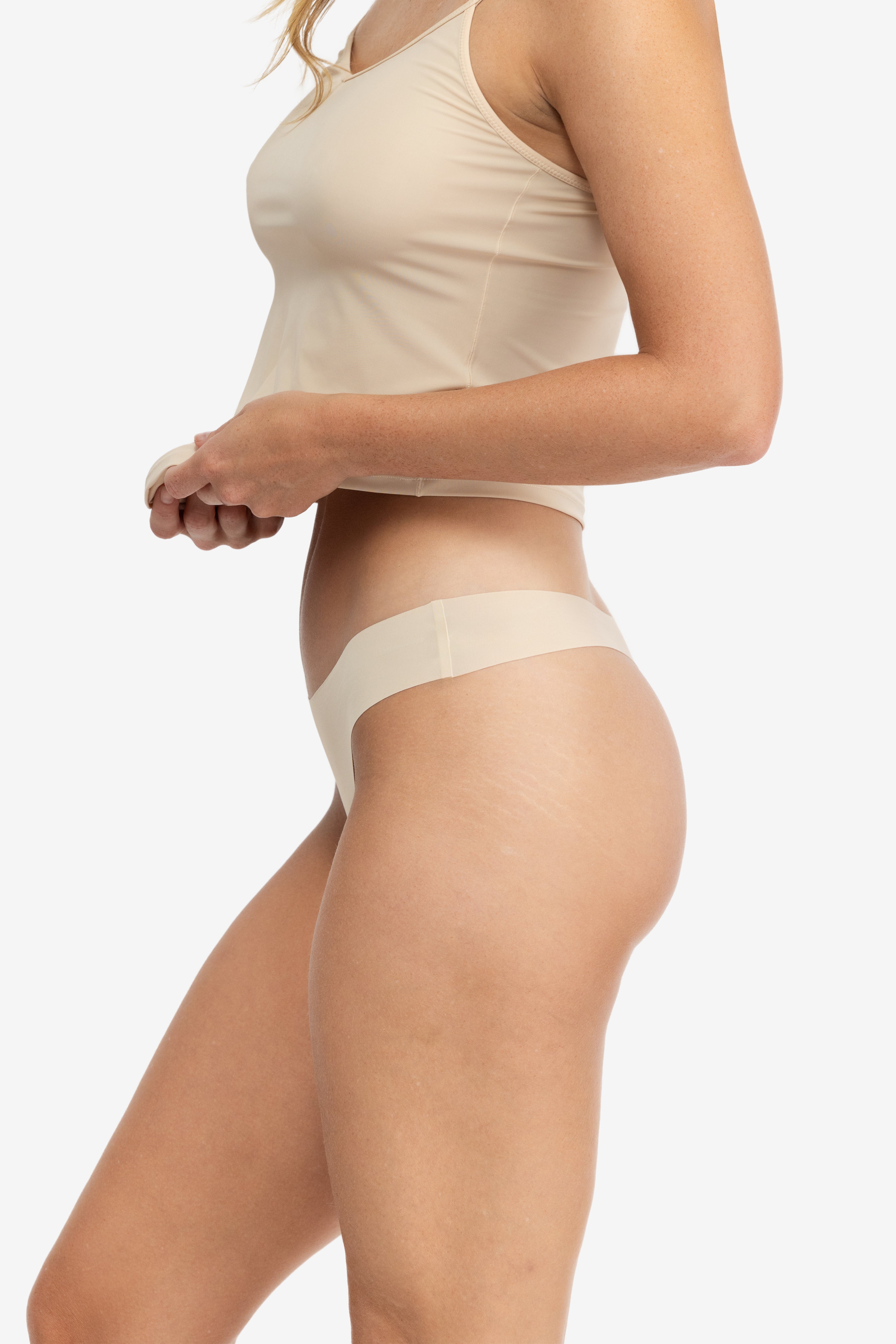 A woman wearing a smoke grey soft seamless thong underwear on white background.