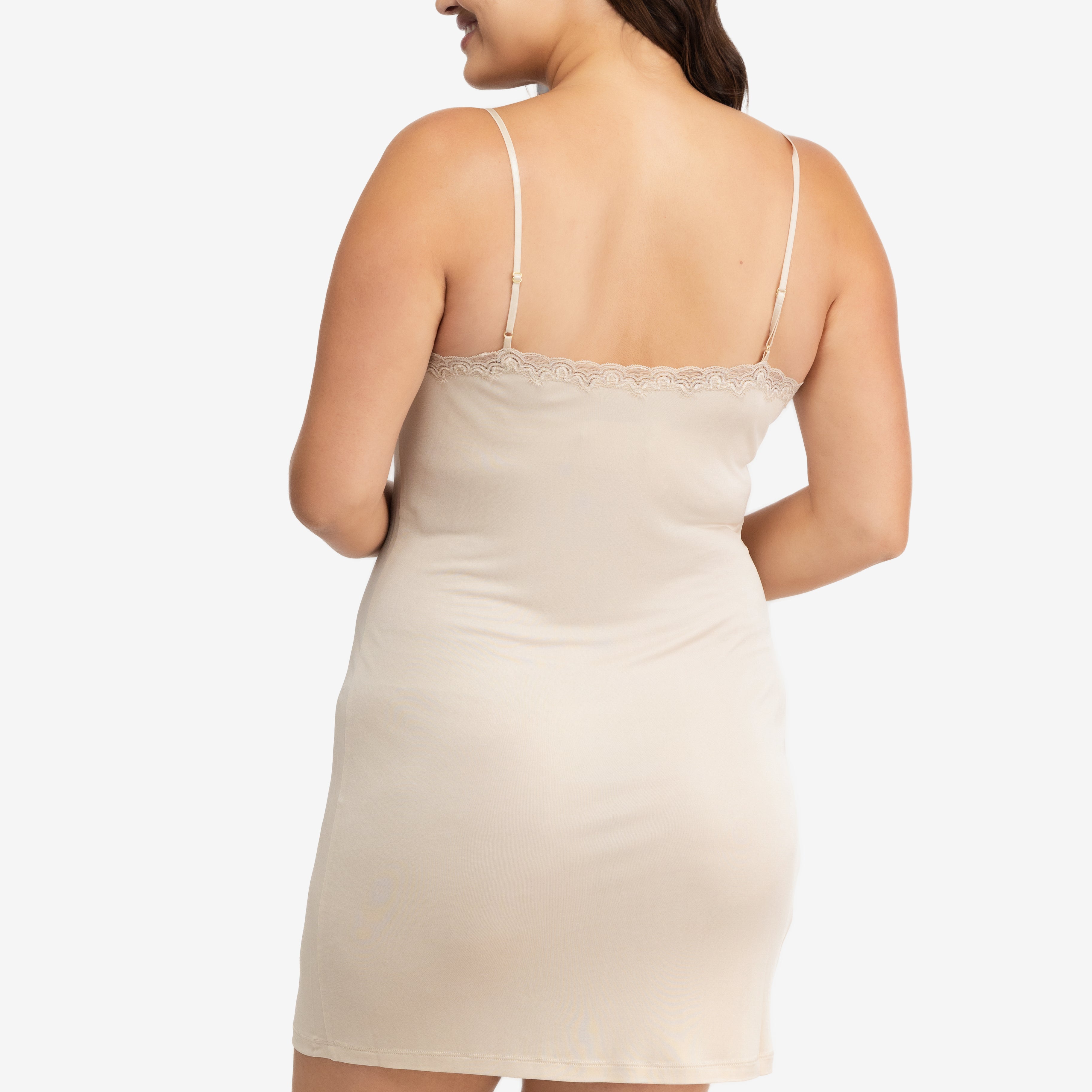 A woman wearing a smoke grey silk blend slip with adjustable spaghetti straps and lace trim at the neckline.