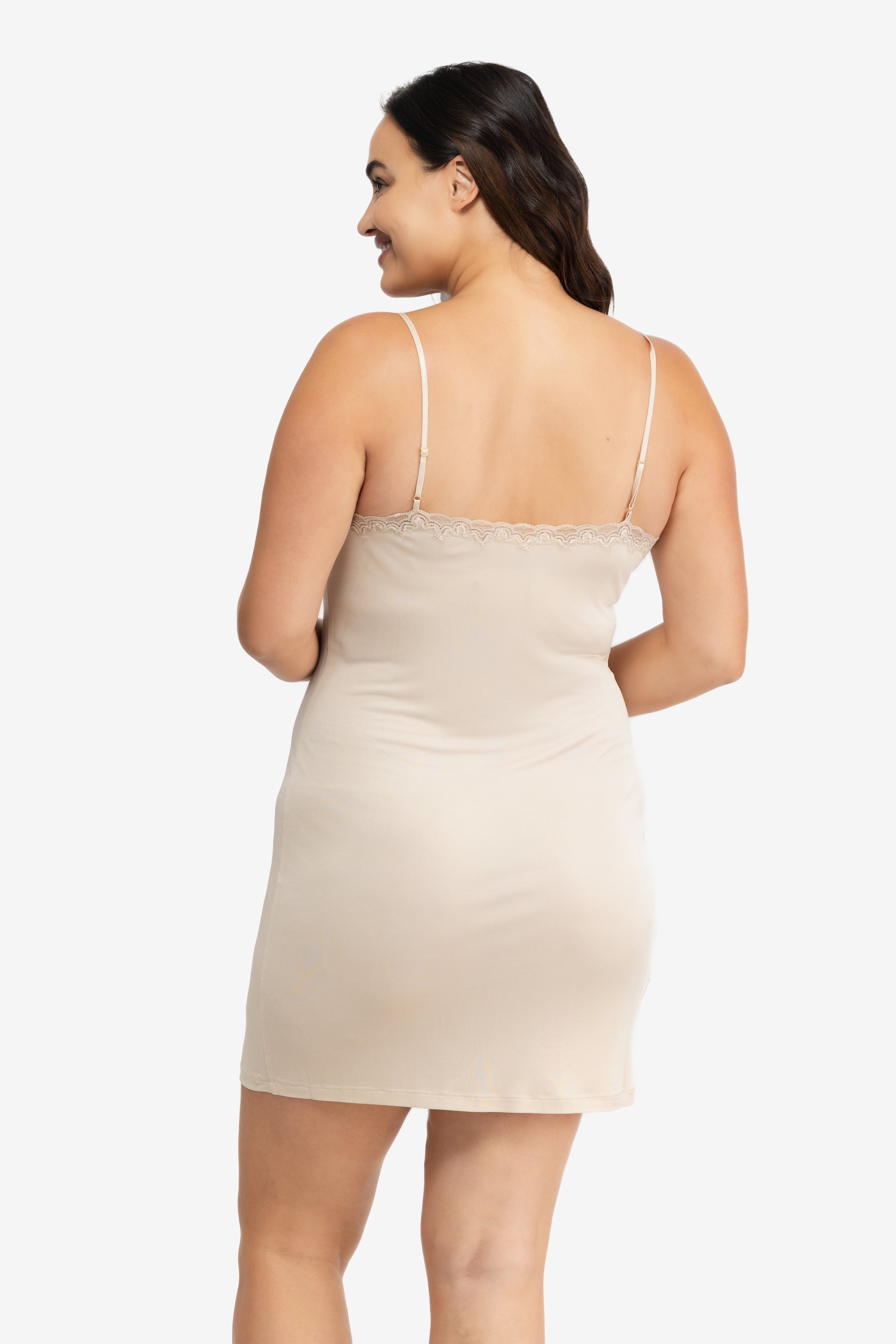 A woman wearing a smoke grey silk blend slip with adjustable spaghetti straps and lace trim at the neckline.