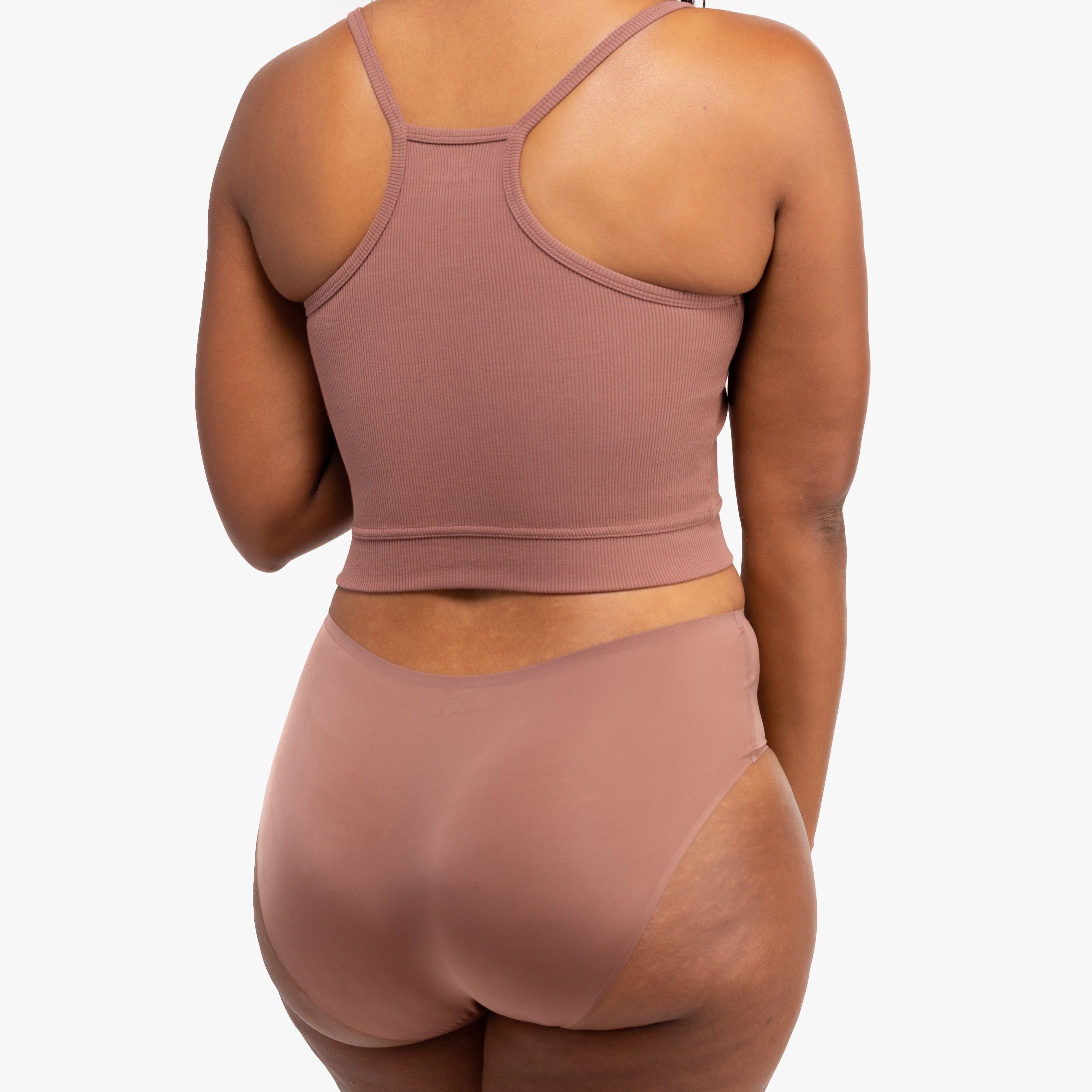 A woman wearing Toffee bralette with thin straps and a ribbed texture with toffee briefs on white background.