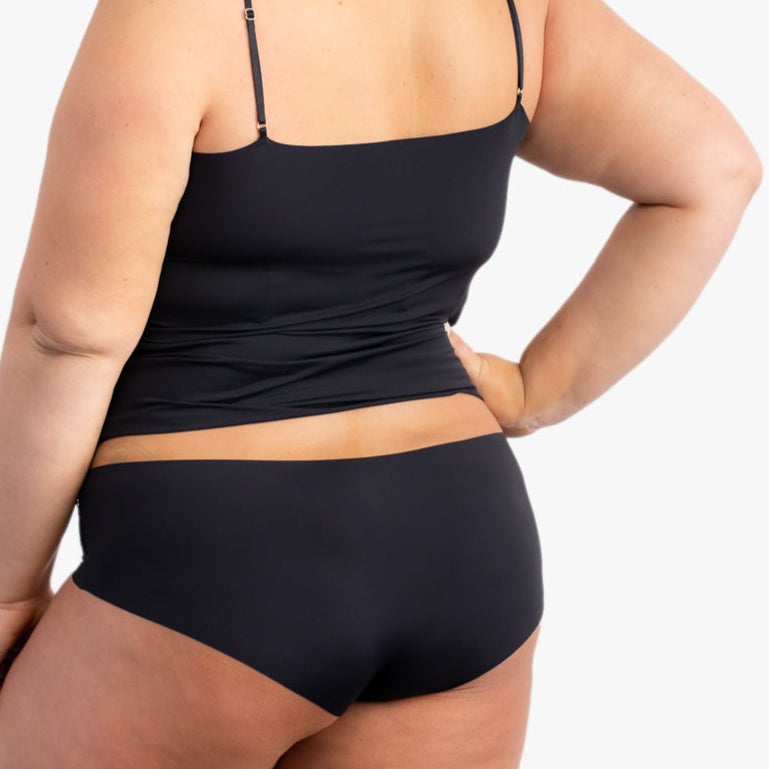 A woman wearing a tap shoe black soft seamless underwear briefs and cami set with lace details.