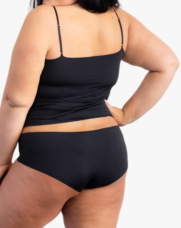 A woman wearing a tap shoe black soft seamless underwear briefs and cami set with lace details.