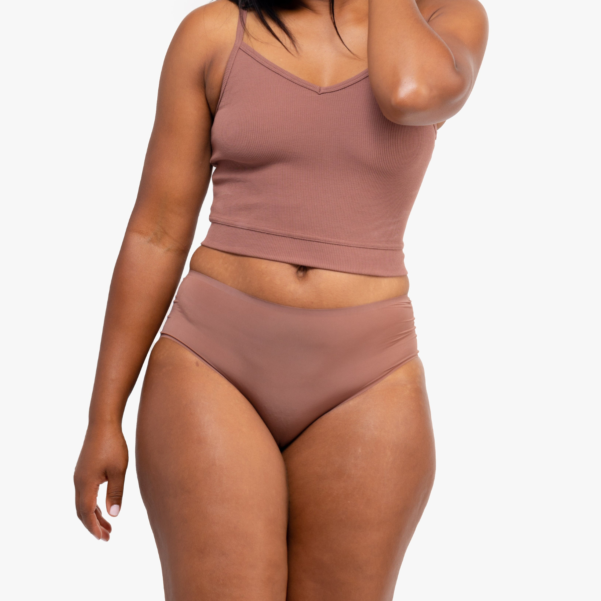 A woman wearing Toffee bralette with thin straps and a ribbed texture with toffee briefs on white background.