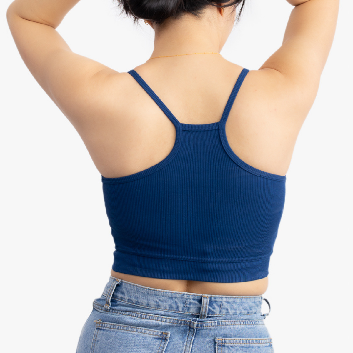 A woman wearing Estate blue bralette with thin straps and a ribbed texture on white background.