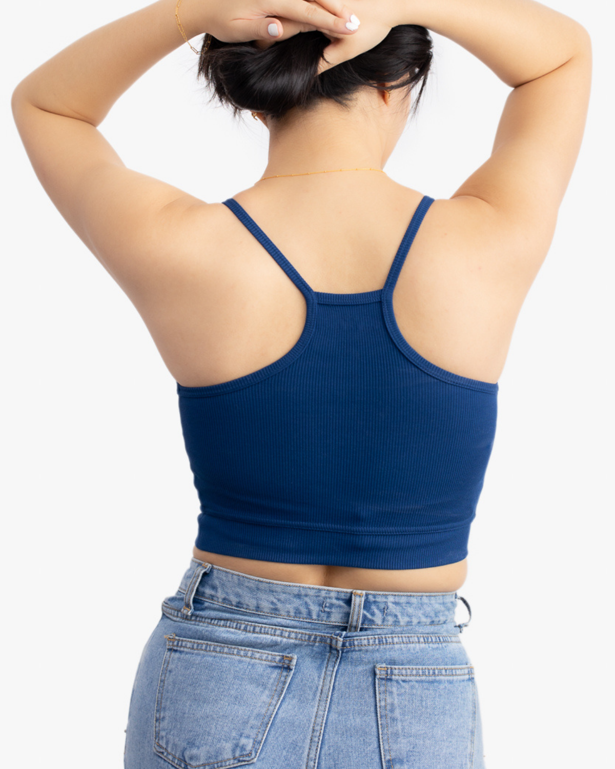 A woman wearing Estate blue bralette with thin straps and a ribbed texture on white background.