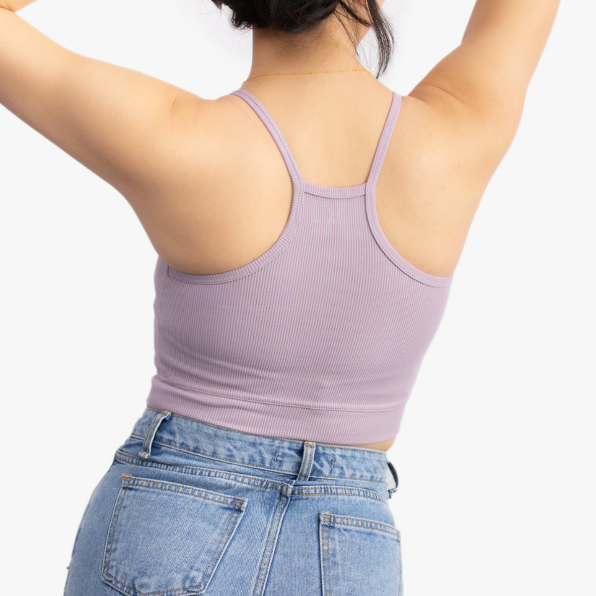 A woman wearing a nirvana bralette with thin straps and a ribbed texture on white background.