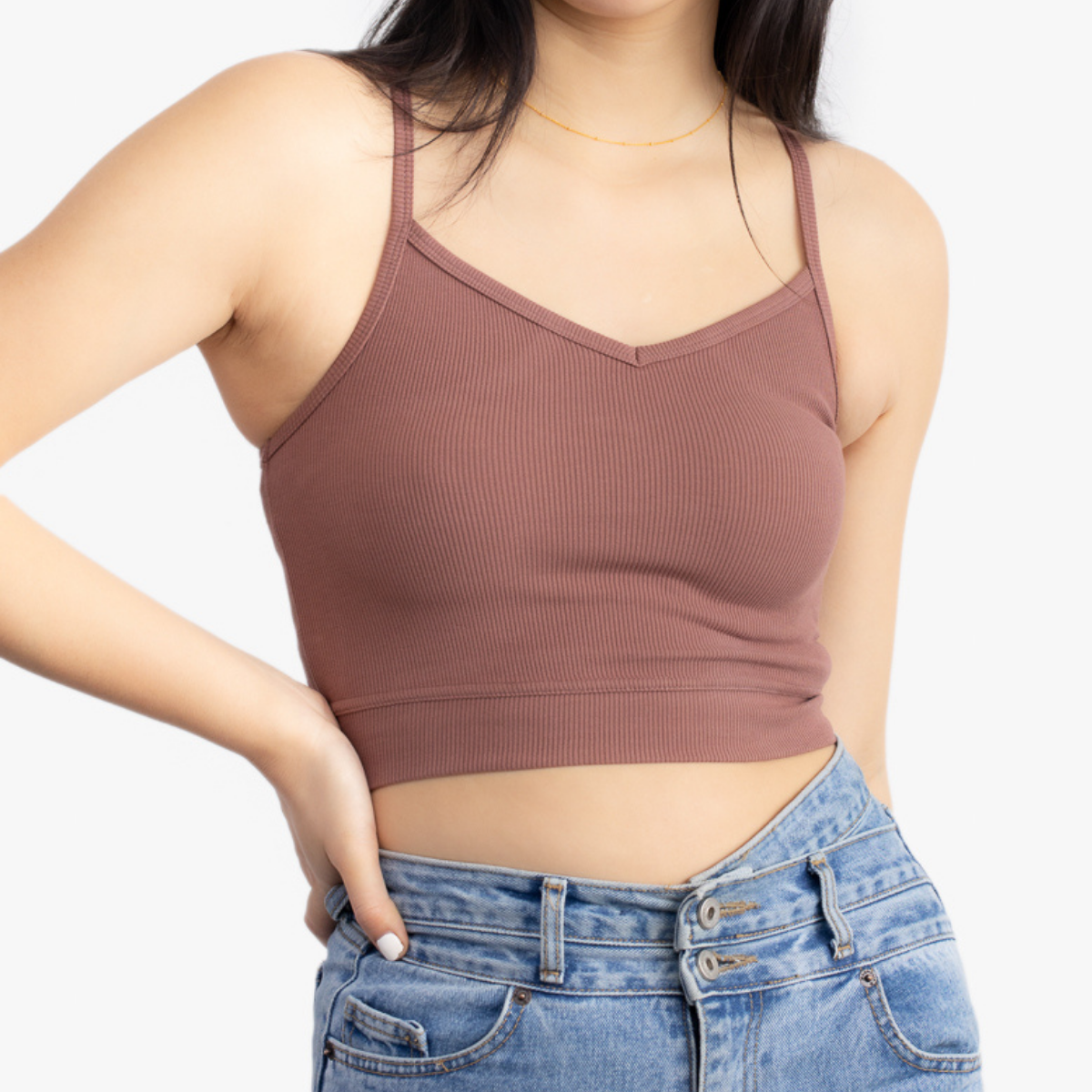 A woman wearing Toffee bralette with thin straps and a ribbed texture with jeans on white background.