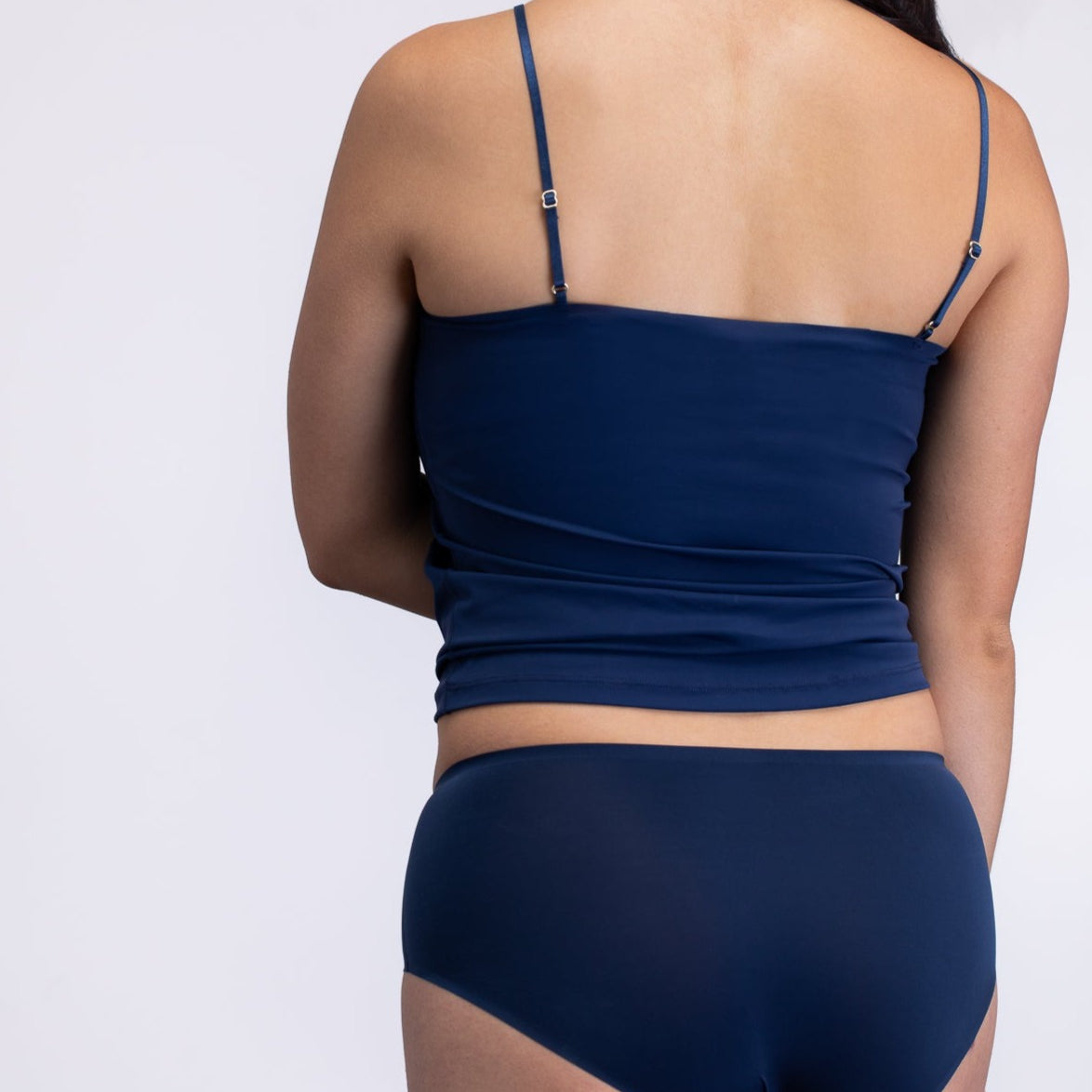 Woman wearing a Dress blue soft seamless lace-trimmed camisole against white background.