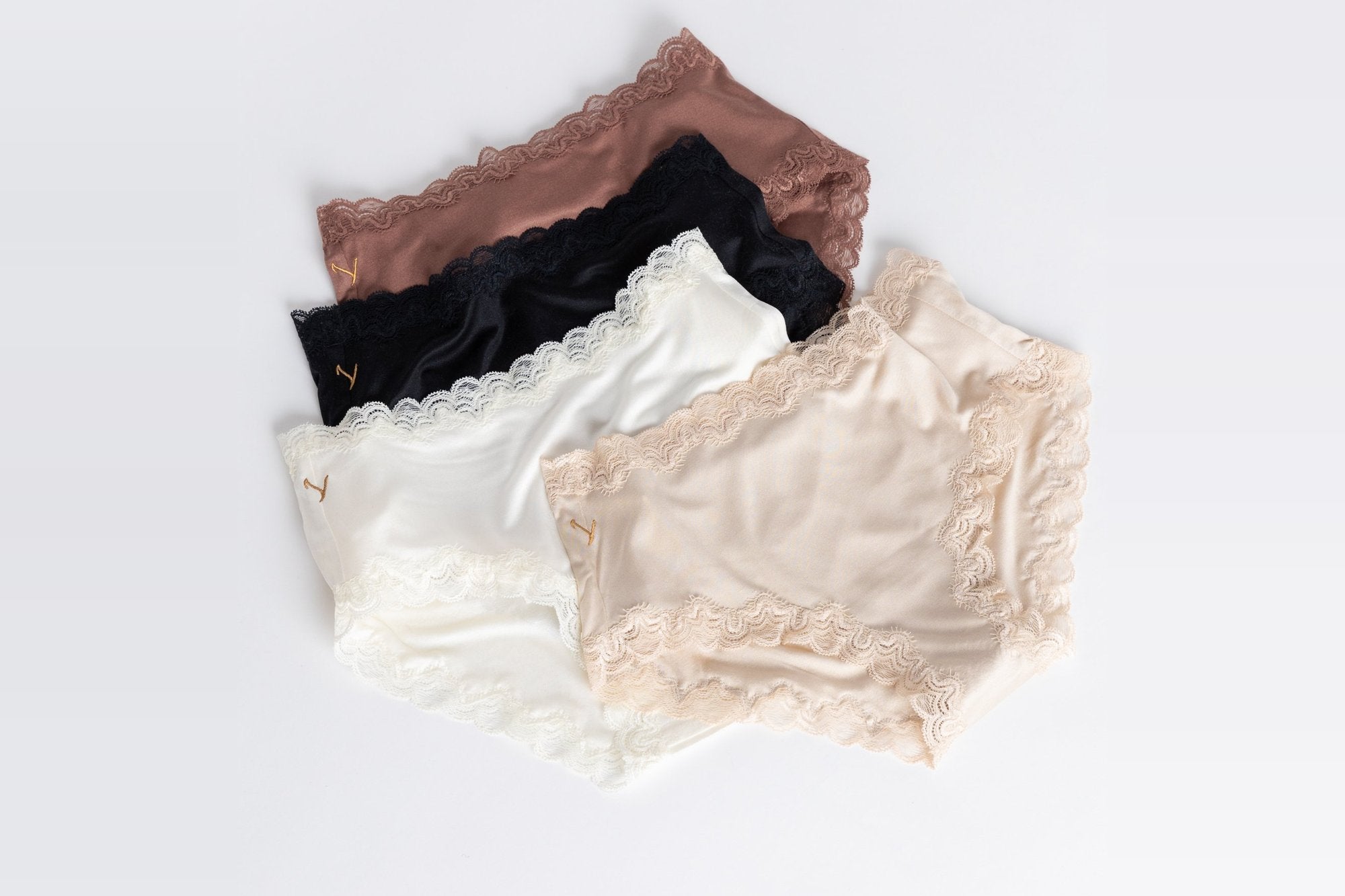 Four pairs of Uwila Warrior Soft Silk briefs with lace trim in brown, black, ivory and champagne