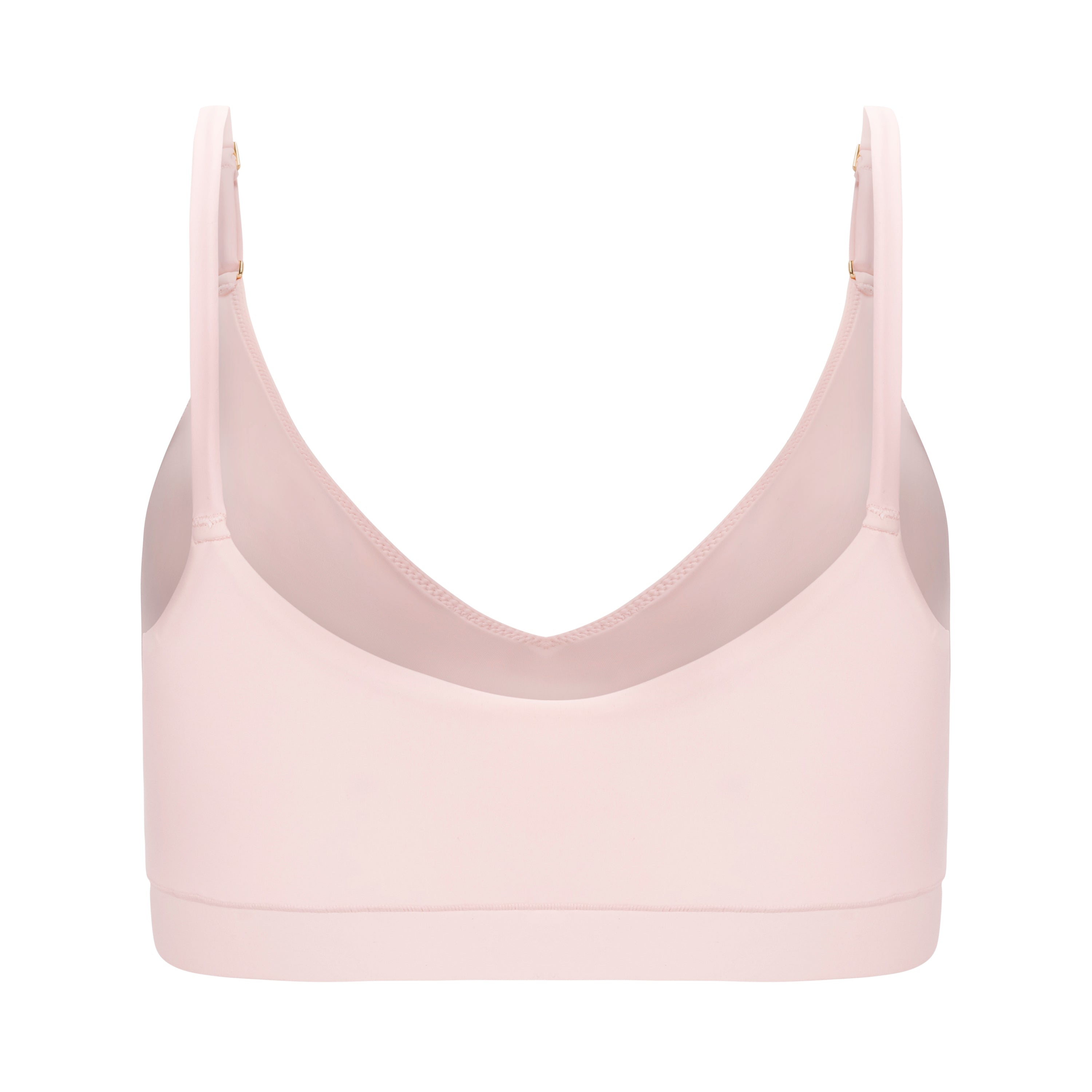 A rose quartz underwire-free soft bra with adjustable straps and removable cup inserts on white background.