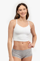 A woman wearing a white bralette with thin straps and a ribbed texture on white background.