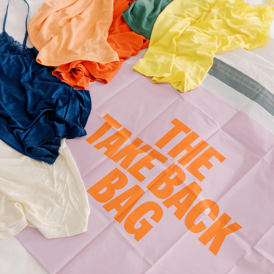 A flat lay of various soft silk camisoles and  'THE TAKE BACK BAG' prominently displayed in orange on a pink background.
