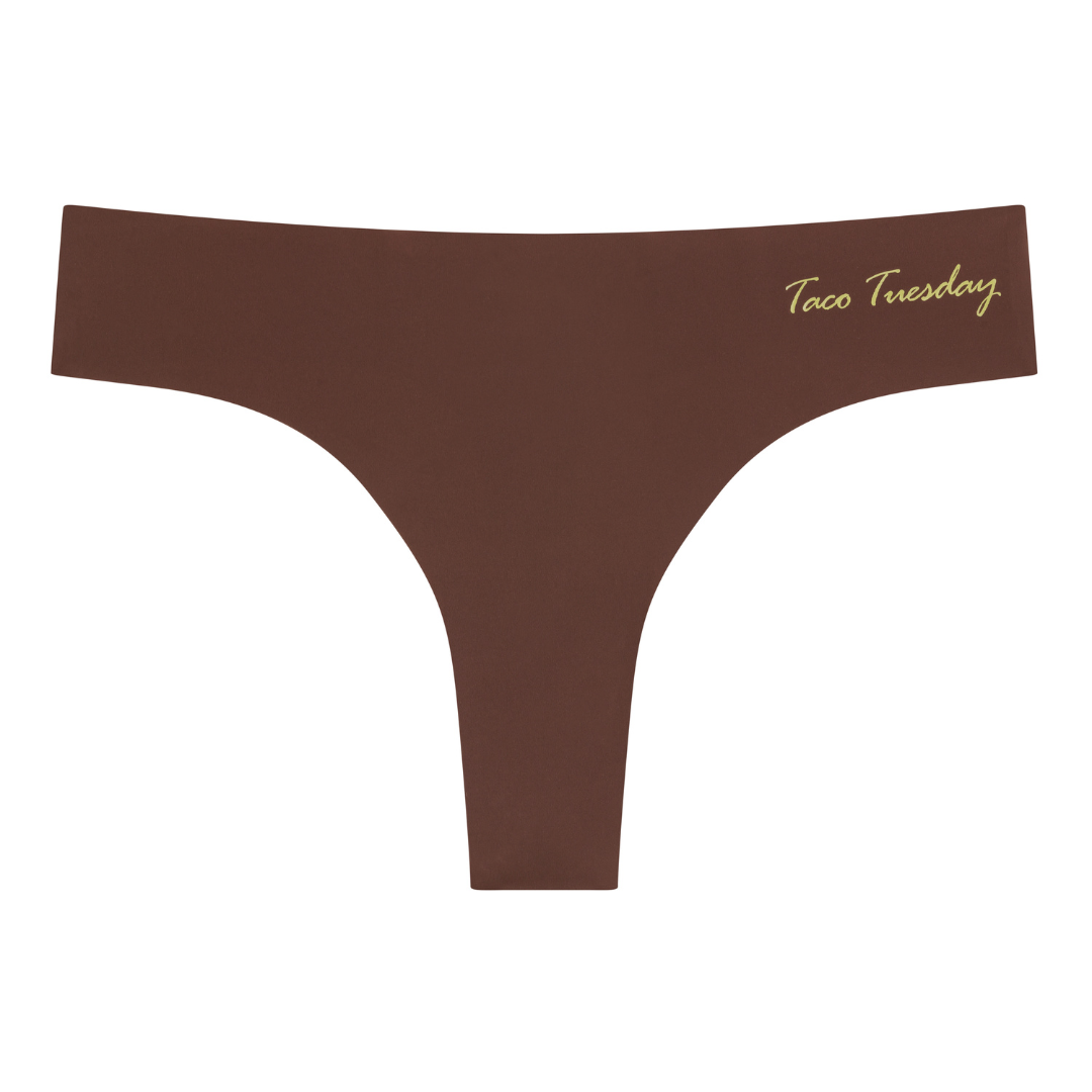 A chocolate soft seamless thong with 'Taco Tuesday' written in gold on the front.