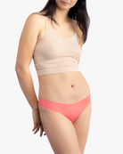 A woman wearing a calypso coral soft seamless thong underwear on white background.
