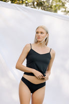 A woman wearing a tap shoe black soft seamless thong underwear on white background.