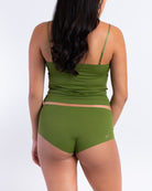 A woman wearing a kale soft seamless lace-trimmed camisole against a white background.