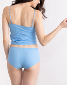 A woman wearing a light blue soft seamless camisole with delicate lace detail at the neckline, with adjustable straps.
