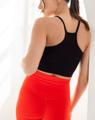 Person wearing a black sports bra and red leggings against a white background