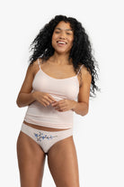 Woman wearing a soft seamless camisole with adjustable spaghetti straps and a V-neckline on white background.