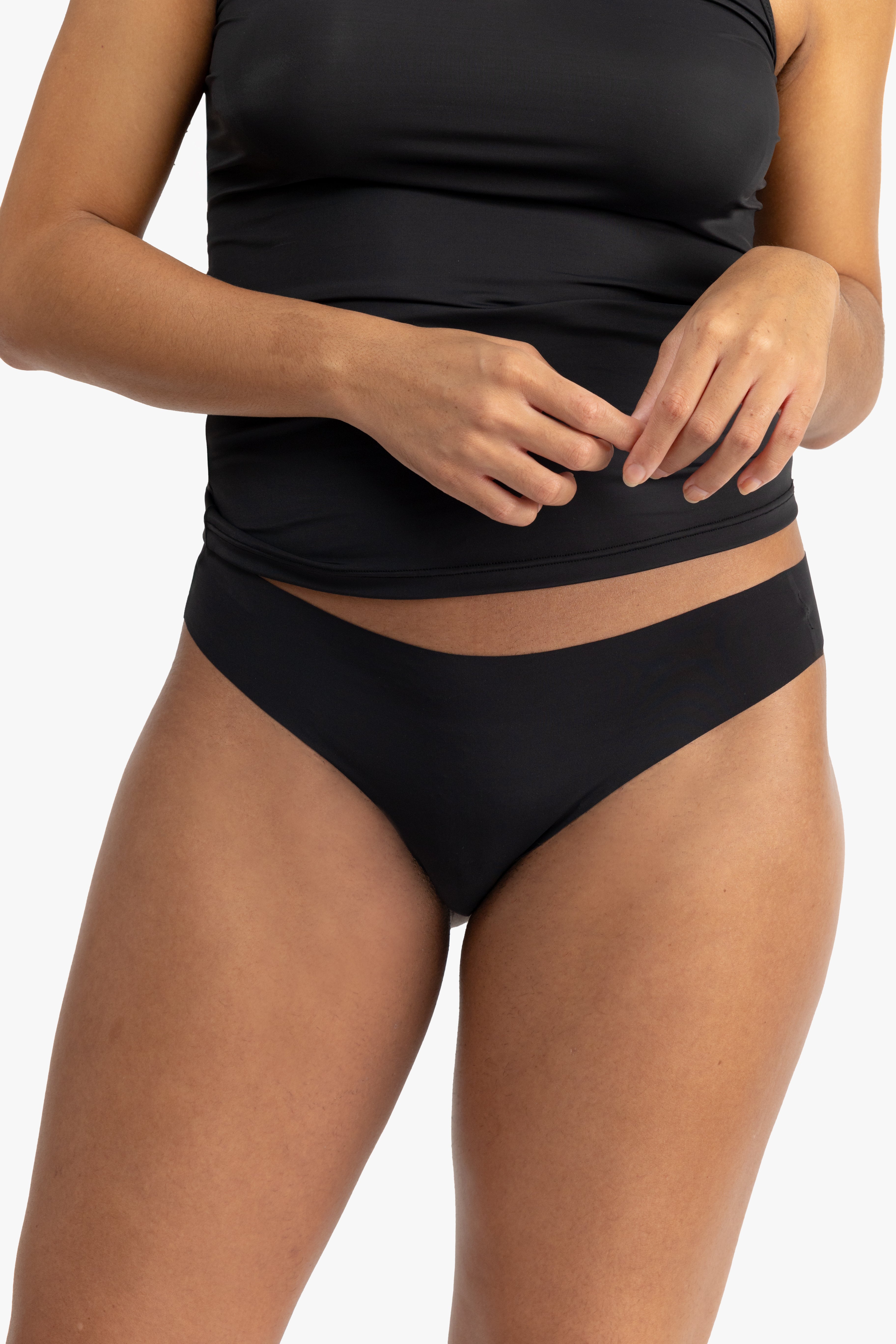 A woman wearing a tap shoe black soft seamless thong underwear on white background.