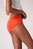 Model wearing Spicy Orange bright Soft Silk Briefs with lace trim on a white background