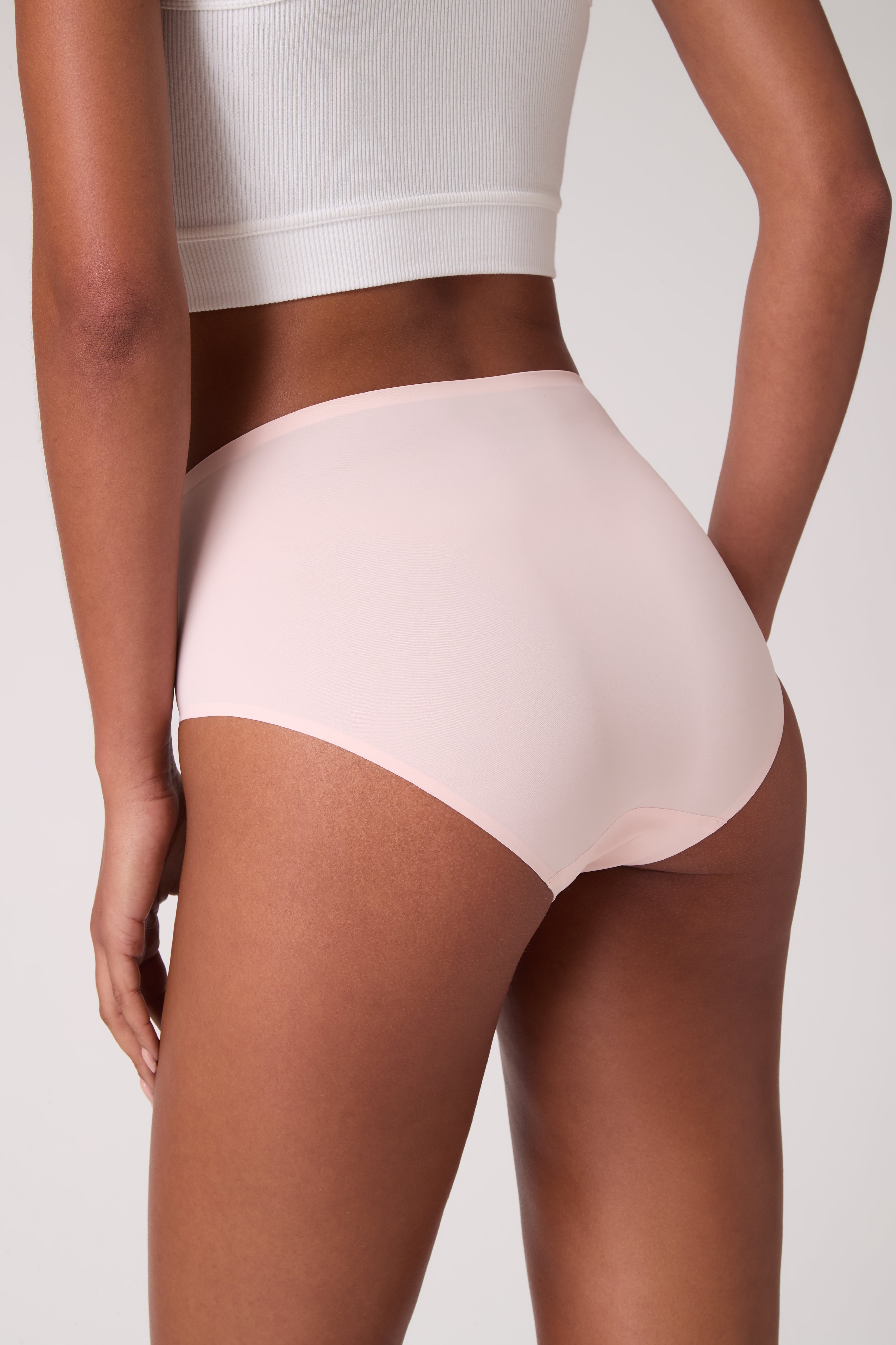 Back view of model wearing Rose Quartz UW Soft Seamless High Waist Brief on white background.