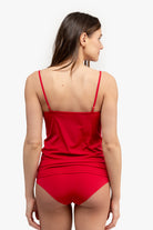 A woman wearing a red soft seamless camisole with adjustable spaghetti straps and a V-neckline on white background.