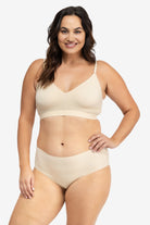 A woman wearing a smoke grey, underwire-free soft bra with adjustable straps and removable cup inserts on white background.