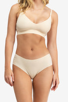 A woman wearing a smoke grey, underwire-free soft bra with adjustable straps and removable cup inserts on white background.