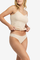 A woman wearing a smoke grey soft seamless thong underwear on white background.