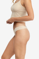 A woman wearing a smoke grey soft seamless thong underwear on white background.