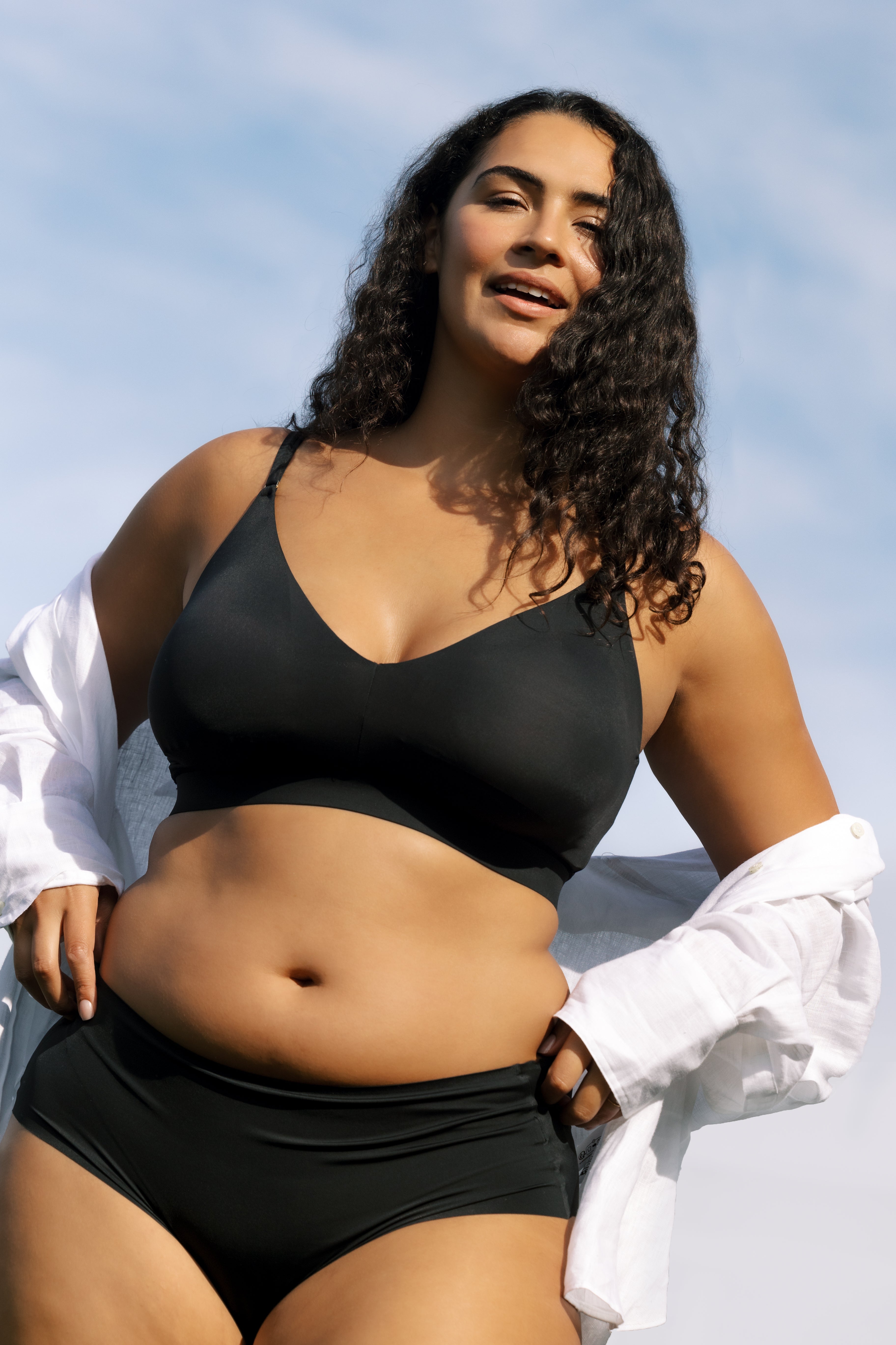 Model wearing Uwila Warrior Better Briefs Soft Bra in Tap Shoe Black on Blue Background